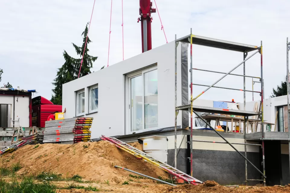 White modular home being built on dirt mound